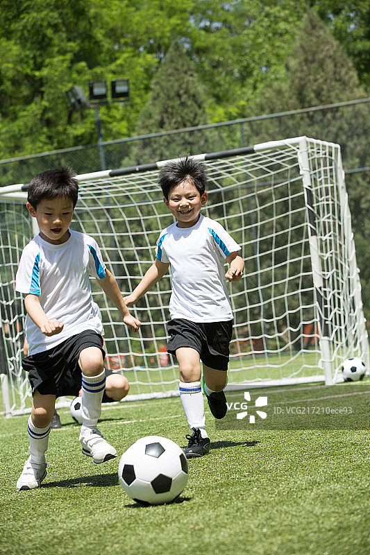 两个男孩在足球场上踢球图片素材
