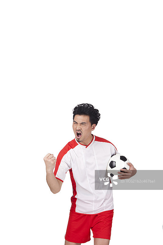 一个穿足球队服抱球呐喊的男青年图片素材