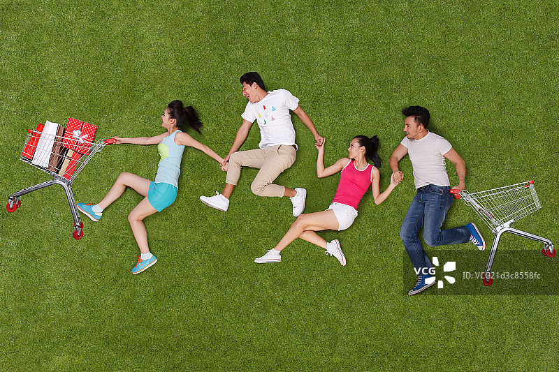 年轻男女在草地上推购物车奔跑图片素材