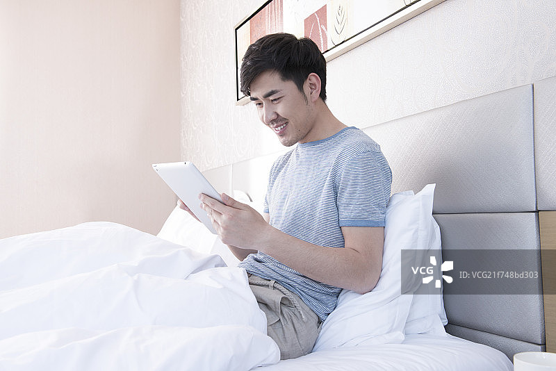 Young man using tablet in bed图片素材