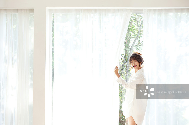 一个女人站在明亮的窗户前图片素材