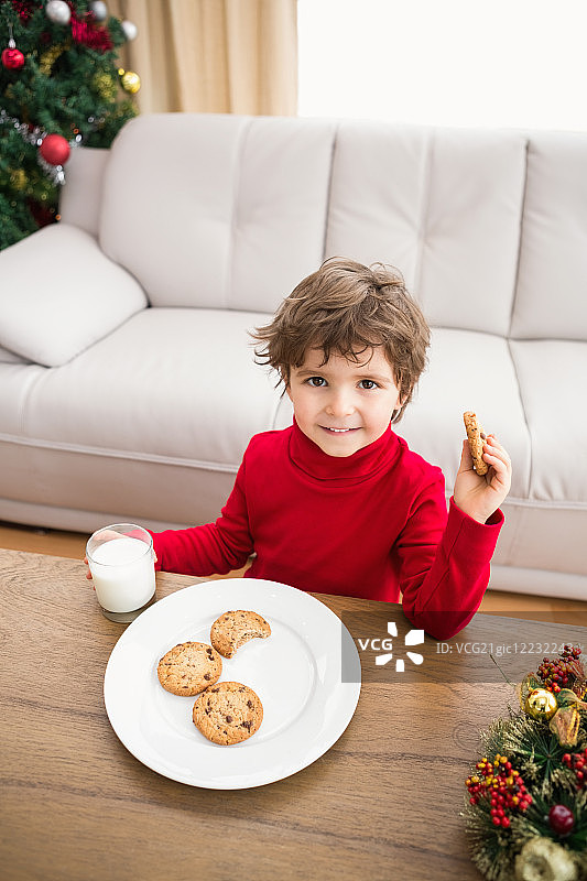 欢乐的小男孩在客厅里喝着牛奶和吃着饼干图片素材