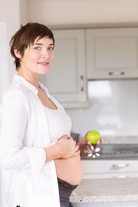 一个孕妇在厨房里拿着苹果图片素材