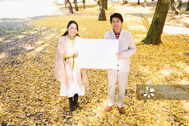 一对日本老年夫妇在城市公园里拿着白板图片素材