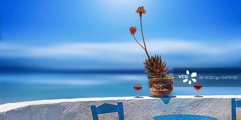 邀请椅子和桌子在阳台上与大海的景色，圣托里尼，希腊图片素材