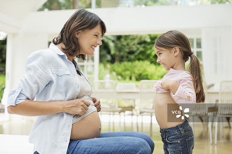 女孩和怀孕的母亲比较肚子图片素材