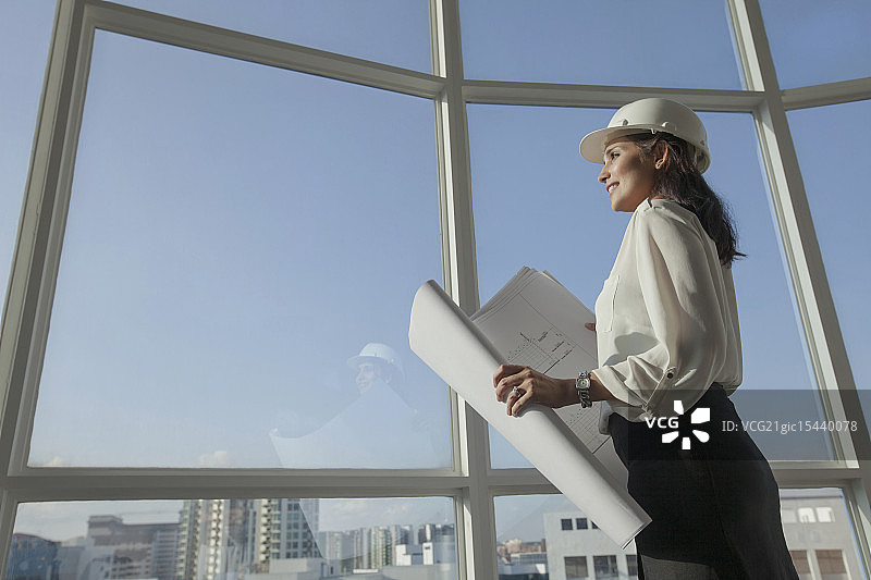 新加坡，女建筑师，戴安全帽，透过窗户看建筑平面图图片素材