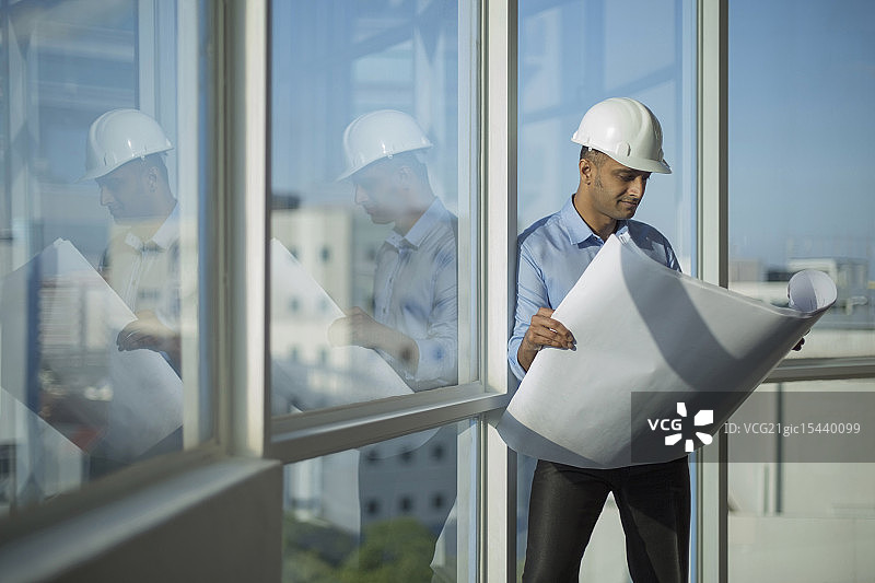 新加坡，男建筑师戴着安全帽看着建筑平面图图片素材