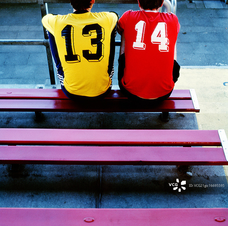 两个穿着足球衫的年轻人坐在板凳上图片素材