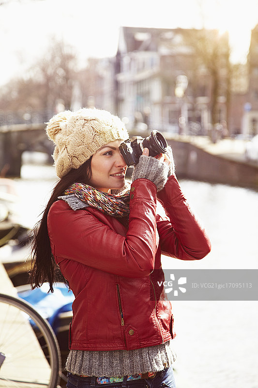 戴着羊毛帽的女人正在用数码相机拍照图片素材