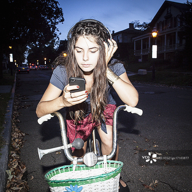 年轻的成年女子骑着自行车用手机图片素材