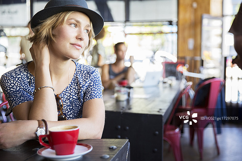 在咖啡馆里，戴着咖啡的沉思女人图片素材