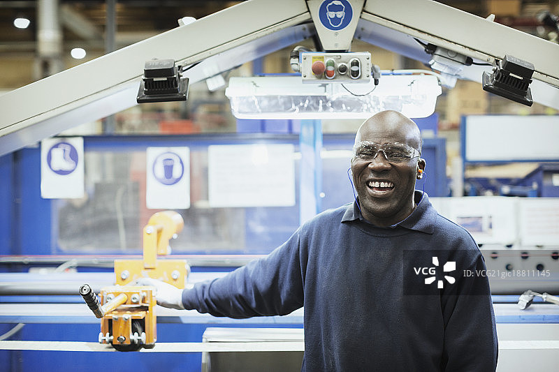 在钢铁厂的机器旁微笑的工人图片素材