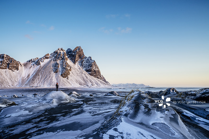 一名女子站在冰岛霍芬偏远冰冷的风景中图片素材