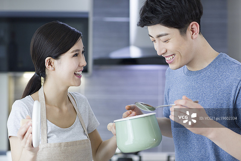 快乐的年轻夫妇在厨房做饭图片素材