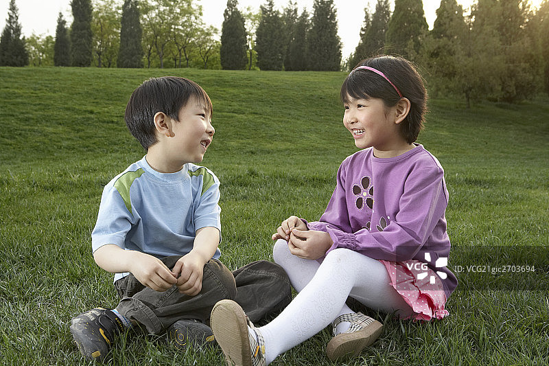 小男孩和小女孩坐在草地上图片素材