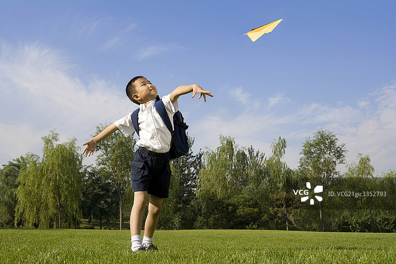 在草地上玩纸飞机的小男孩图片素材