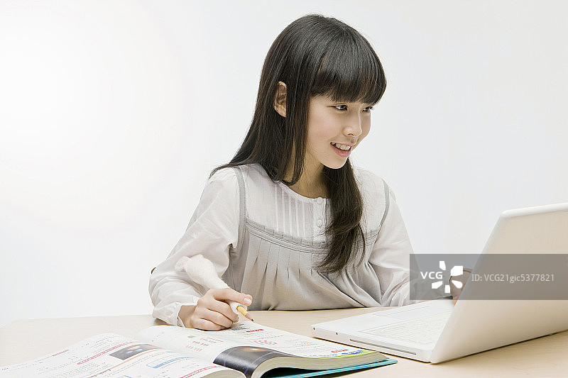 坐在书桌前使用笔记本电脑的女孩图片素材