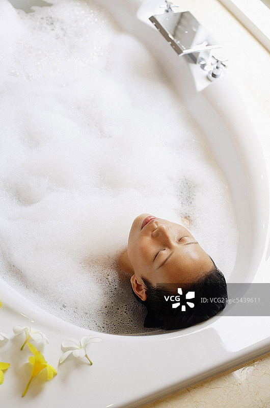 在浴缸里的女人，闭着眼睛，高角度观察图片素材