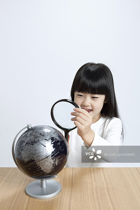 小女孩用放大镜看地球仪图片素材