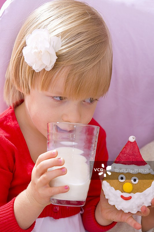 小女孩喝着牛奶，手里拿着饼干图片素材