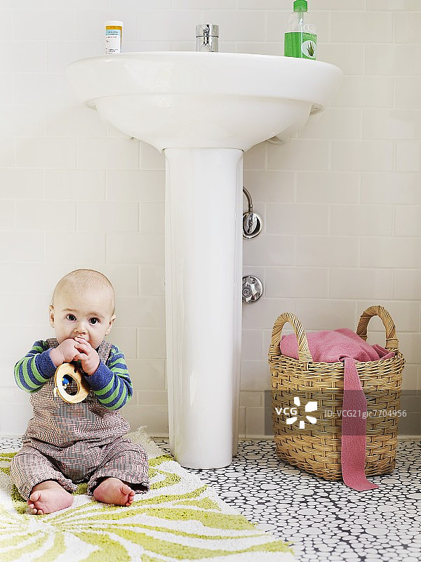婴儿坐在浴室的地毯上图片素材