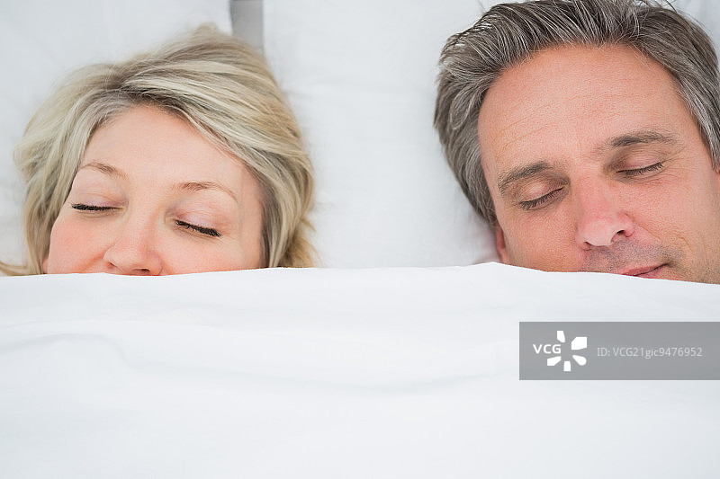 一对夫妇在家里的床上盖着被子睡觉图片素材