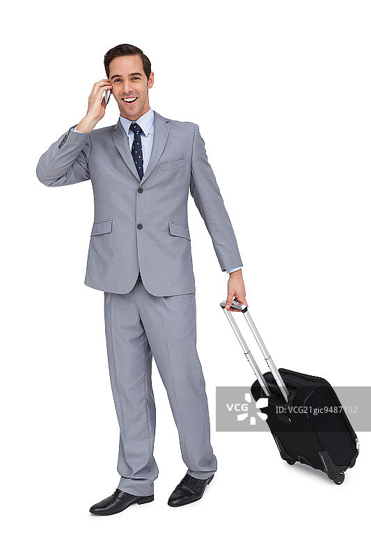 快乐的年轻商人与他的行李，而电话在白色背景图片素材