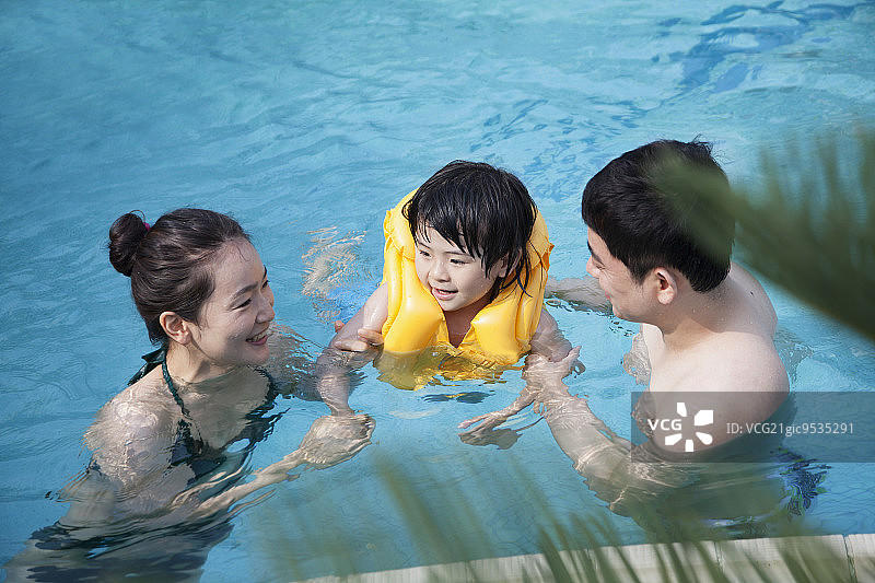 幸福微笑的家庭教儿子如何在游泳池游泳图片素材