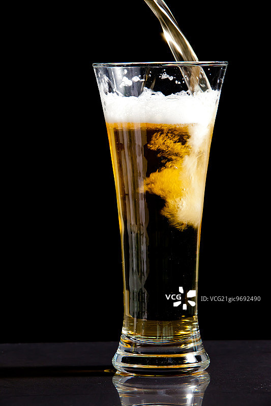 在黑色背景下，装满啤酒的玻璃杯图片素材