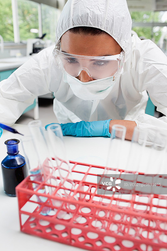 一名受保护的女科学家在实验室的试管中滴蓝色液体的肖像图片素材