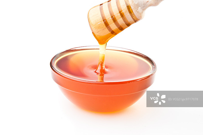 蜂蜜勺放在碗上，背景是白色图片素材