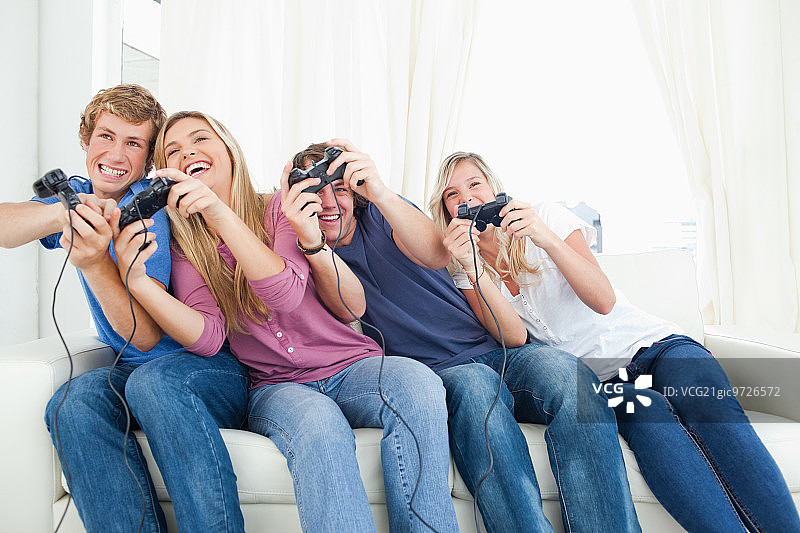 一群朋友在一起玩电子游戏，身体靠在一边。图片素材