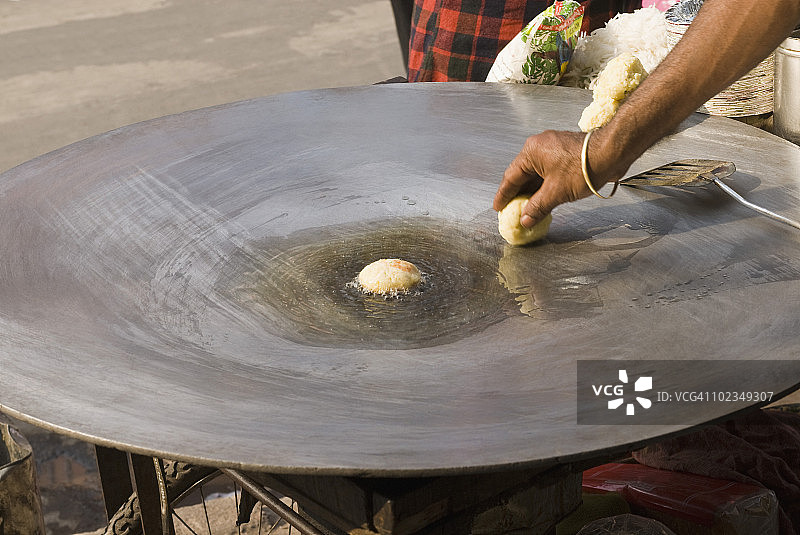 印度德里，一名男子在煎锅上煎咖喱图片素材