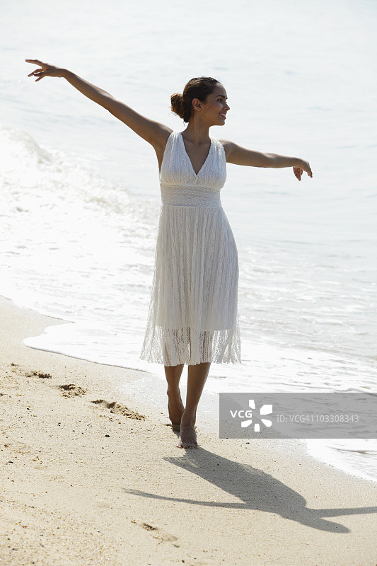 一名年轻女子在海滩上伸开双臂图片素材
