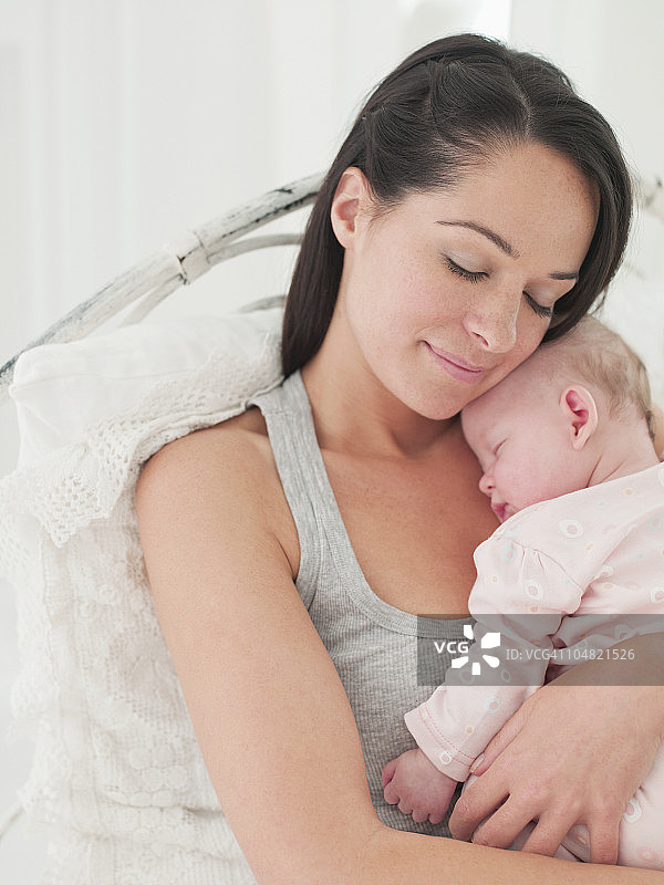 微笑的母亲抱着熟睡的婴儿图片素材