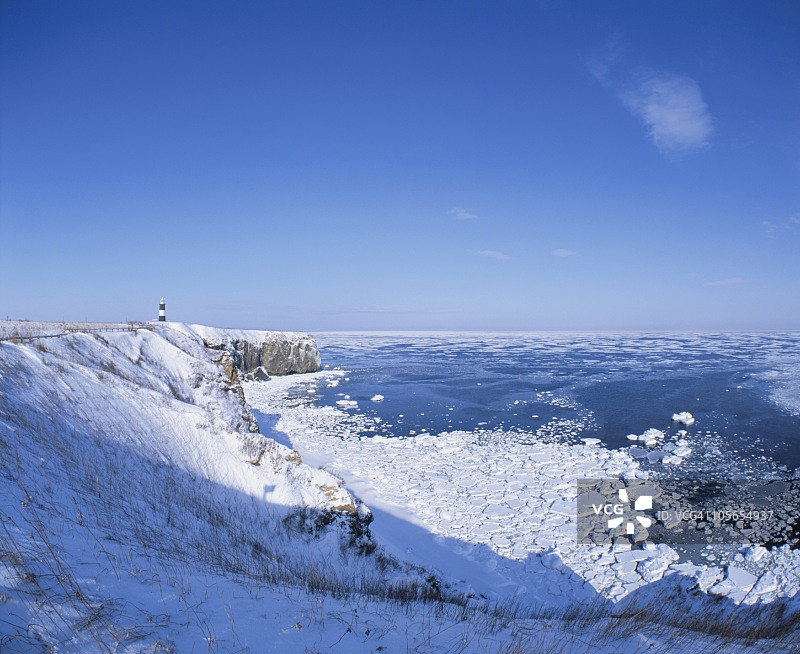 灯塔上的雪山悬崖俯瞰漂移的冰和海洋。男子,日本北海道图片素材