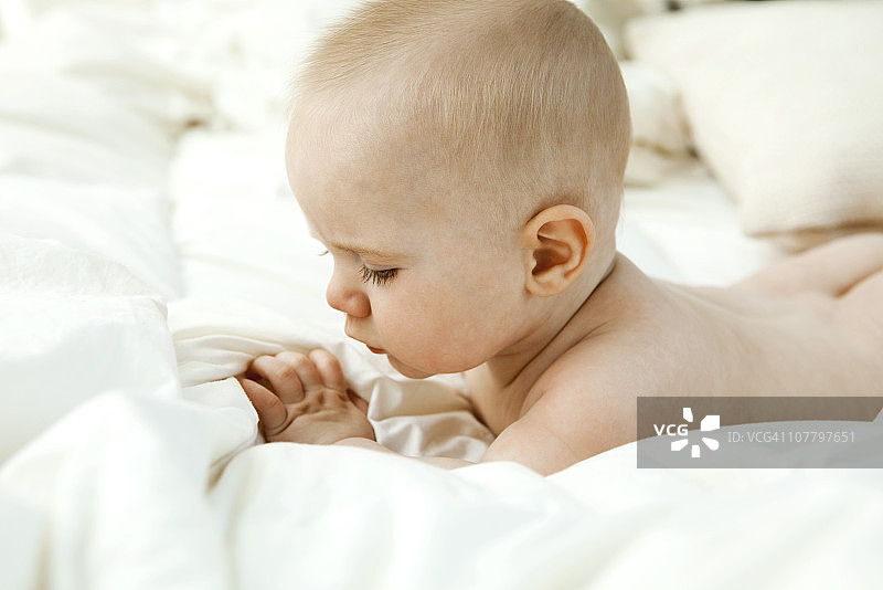 婴儿躺在床上，看着手指图片素材