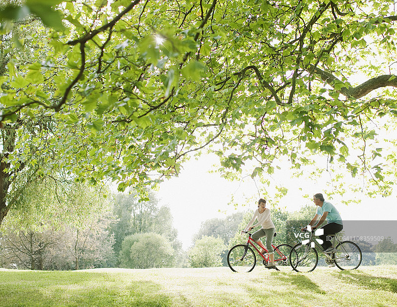 一对夫妇在树下骑自行车图片素材