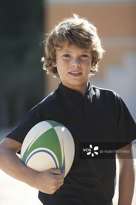 一个拿着橄榄球的男孩的肖像图片素材