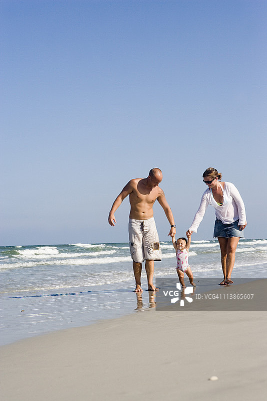 年轻的家庭漫步在海滩上图片素材