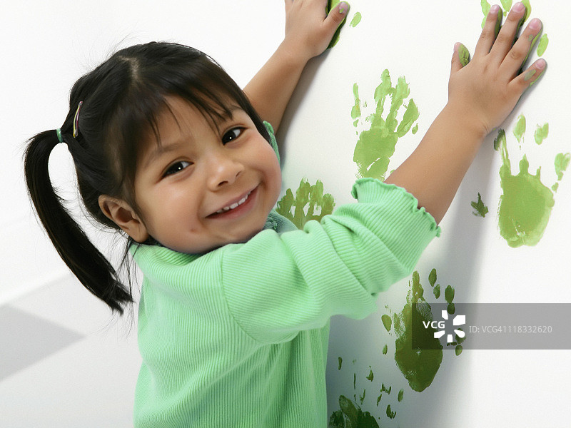 年轻的女孩正在做绿色的手印图片素材