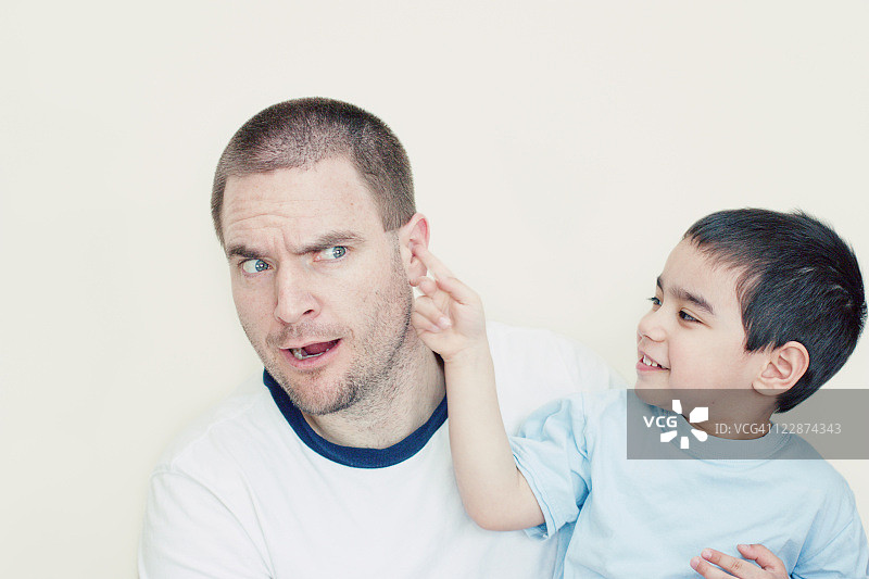 男孩戳他爸爸的耳朵图片素材
