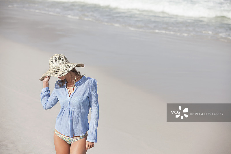 高角度的女人戴着帽子在海滩上图片素材