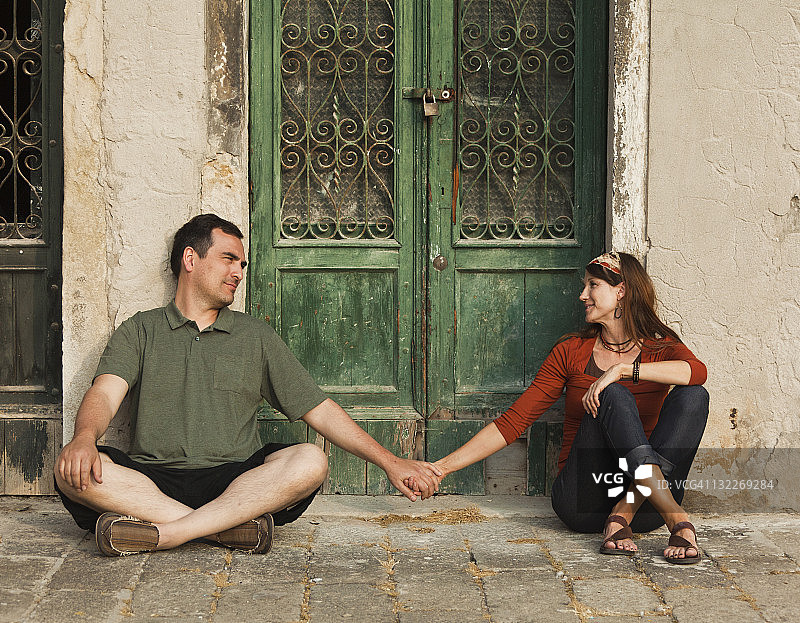 意大利，威尼斯，老城区的木门上牵着手的夫妇图片素材