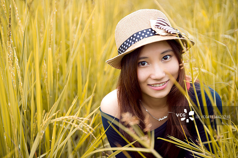戴着帽子的女人坐在稻田里图片素材