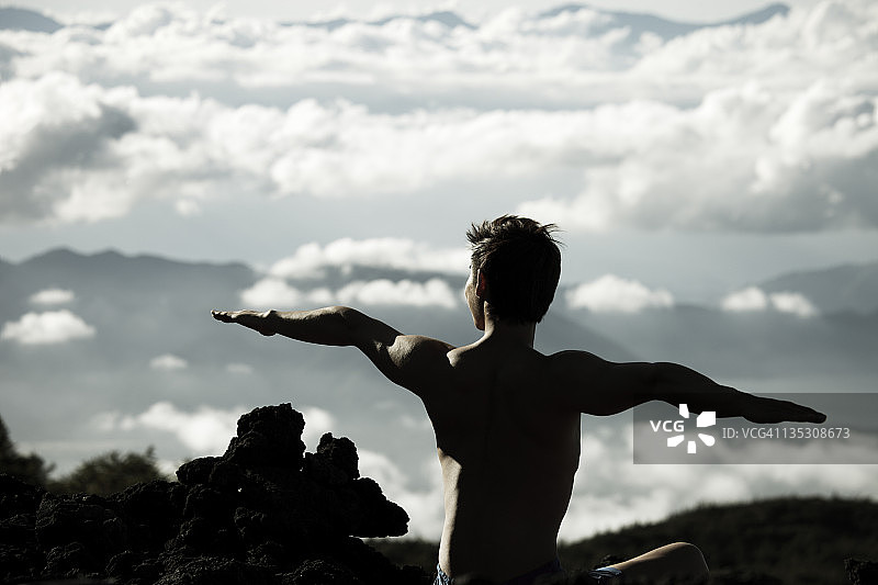 一个在山上做瑜伽的年轻人图片素材