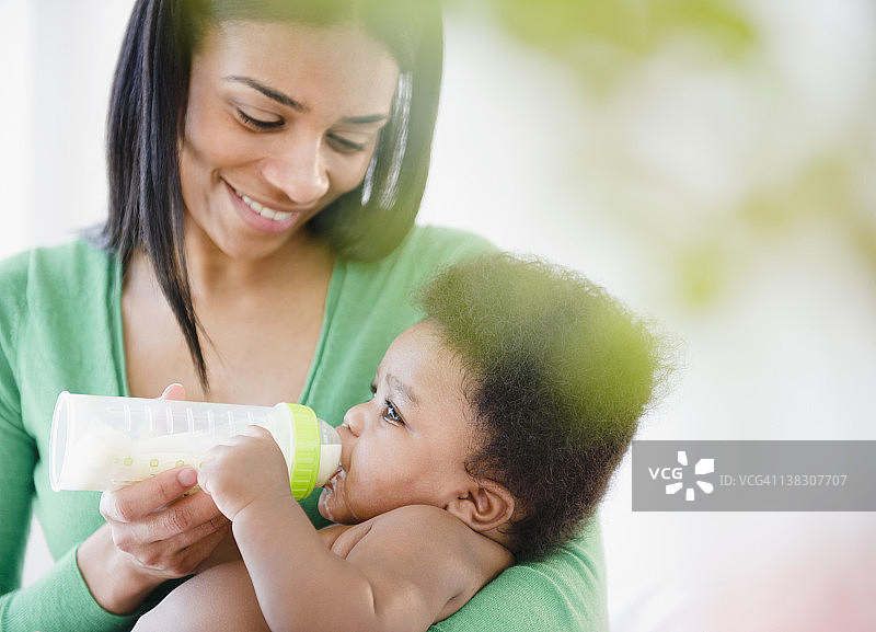 非裔美国母亲用奶瓶喂男婴图片素材