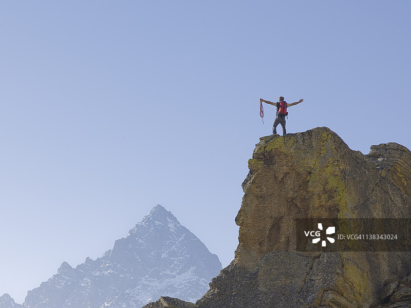 攀登者站在山顶，双臂伸展着图片素材