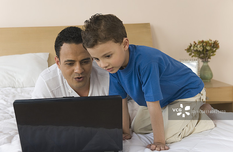 男人和他的儿子在用笔记本电脑图片素材